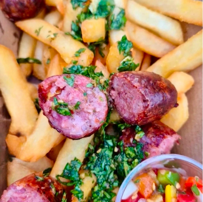 Grilled choripán slices over chips with chimichurri